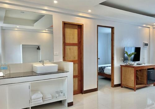 een badkamer met een wastafel, een spiegel en een bed bij The XIMO Suites in Boracay
