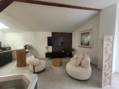uma sala de estar com 2 cadeiras brancas e uma banheira em Appartement d'une chambre avec jacuzzi terrasse et wifi a Duppigheim em Duppigheim