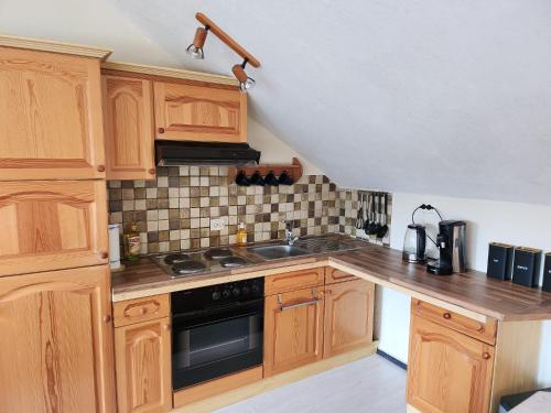 cocina con armarios de madera y horno con fogones en Ferienwohnung Engelsblick, en Winterberg