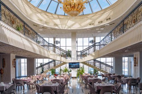 un comedor con mesas y una lámpara de araña en un edificio en Jannat Resort Osh, en Osh