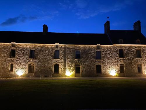 a large stone building at night with lights on it at Maison Galop Marin in Saint-Côme-du-Mont