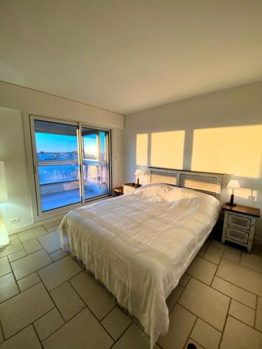 une chambre avec un grand lit et une grande fenêtre dans l'établissement Le Grand Panoramique - Face Mer, à Les Sables-dʼOlonne