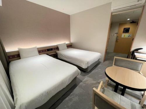 a hotel room with two beds and a table at Henn na Hotel Premier Nara in Nara
