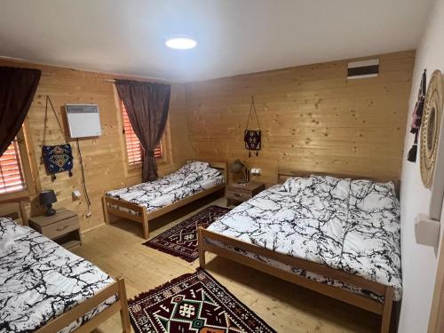 three beds in a room with wooden walls at Etno meandri Uvca in Sjenica