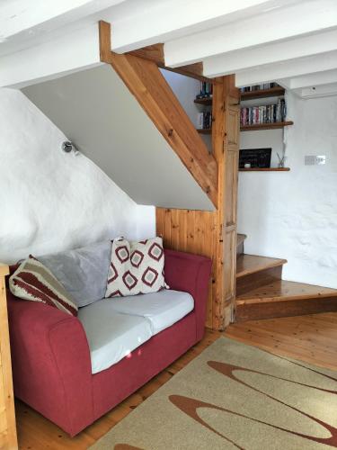 a living room with a red couch and wooden ceilings at The Cosy Pad Glan Y Morfa Bach in Tywyn