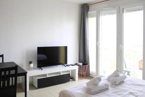 - un salon avec une télévision et un lit avec des serviettes dans l'établissement Cocoon of love at the gates of the City of Light, à Aubervilliers