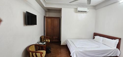 Khách Sạn Ninh Hà في سام سون: غرفة نوم مع سرير وتلفزيون على الحائط