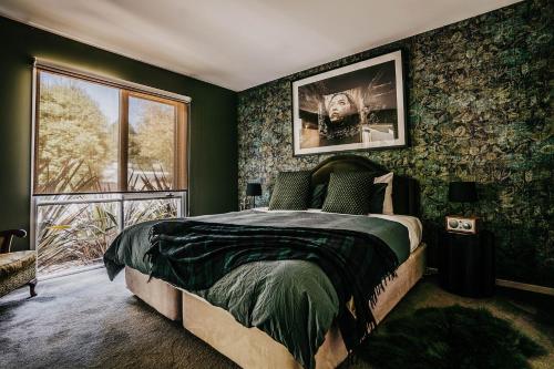 a bedroom with a bed with green walls and a window at Boatshed Villa Yellow Door in Daylesford