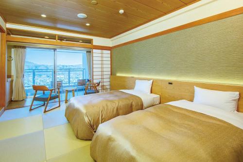 a room with two beds and a table and a balcony at Natural Farm City Noen Hotel in Chichibu