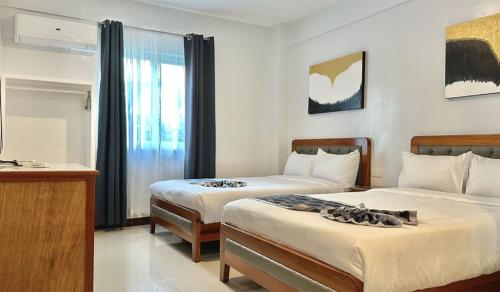 a hotel room with two beds and a television at The XIMO Suites in Boracay