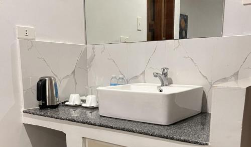 a bathroom counter with a white sink and a mirror at The XIMO Suites in Boracay