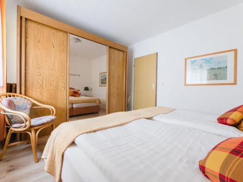 a bedroom with a large bed and a chair at House on the sunny slope type B in Eslohe