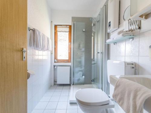 a white bathroom with a toilet and a shower at House on the sunny slope type B in Eslohe