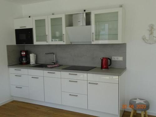 una cocina con armarios blancos y un aparato rojo en Old Printing House Holiday Apartment Bodoni, en Norderney