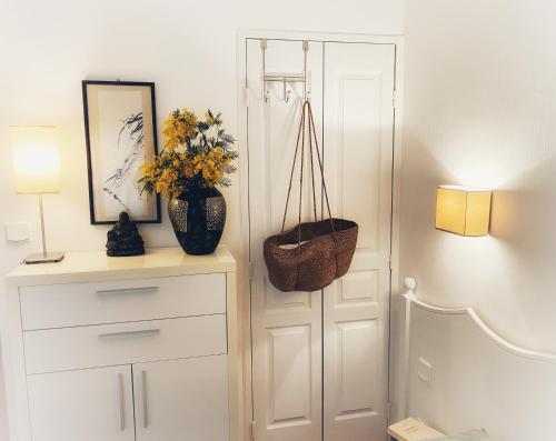 Cette chambre comprend une armoire blanche et un vase avec des fleurs. dans l'établissement Chez Skadi amazing sea view, à Roquebrune-sur Argens