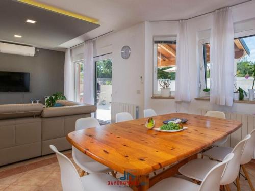 een eetkamer met een houten tafel en witte stoelen bij Nicole Comfortable holiday residence in Pula