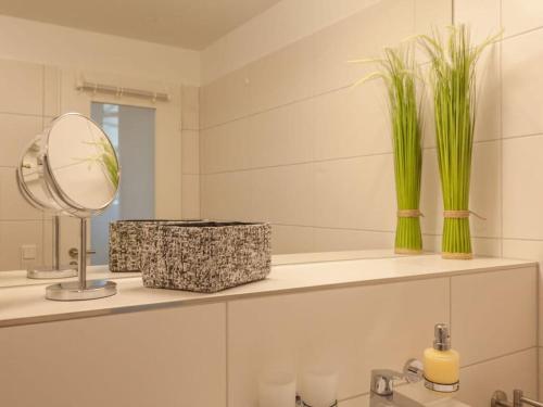 een badkamer met een spiegel en twee planten op een plank bij Dunes Resort Apartment 1 05 in Binz