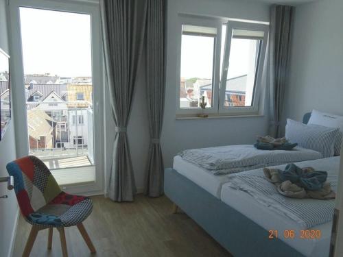 1 dormitorio con 2 camas, silla y ventana en Old Printing House Holiday Apartment Cicero, en Norderney