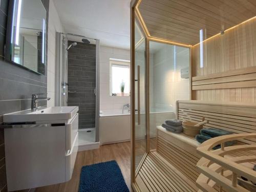 een badkamer met een douche, een wastafel en een bad bij Beachvilla Ijsselmeerblik in Makkum