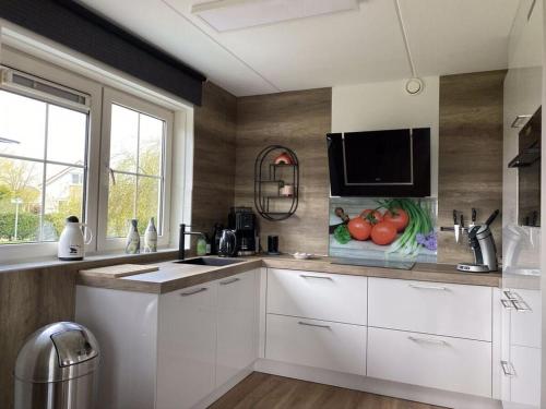 a kitchen with white cabinets and a microwave at Beachvilla Ijsselmeerblik in Makkum