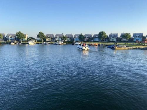 a boat on a river with houses in the background at Beachvilla Ijsselmeerblik in Makkum
