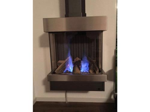 a fireplace with blue flames in a room at Villa Zeezicht Modern retreat in Makkum