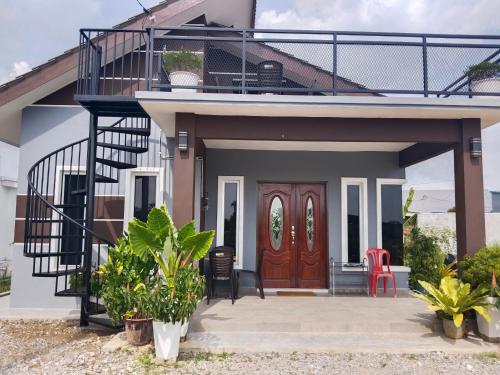 uma casa com uma varanda e uma porta vermelha em Villa Adeeva Homestay Langkawi em Pantai Cenang