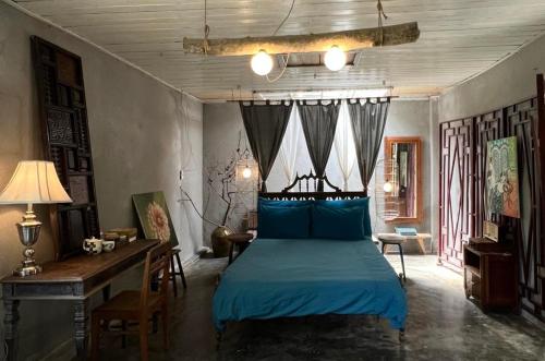 Schlafzimmer mit einem blauen Bett und einem Schreibtisch in der Unterkunft Tre House Dalat in Da Lat