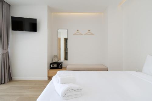 a white bedroom with a bed and a flat screen tv at The Season Resort in Ban Chamrung