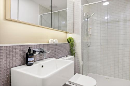 een badkamer met een wastafel, een toilet en een spiegel bij Skyline Treat Apt in Middle of Shopping Haven in Melbourne