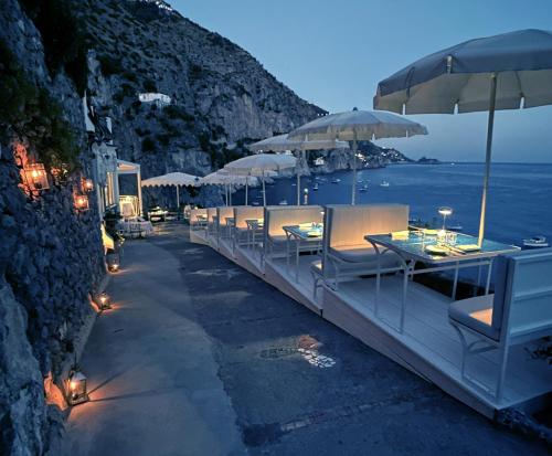 a row of tables and umbrellas on a beach at Villa Corallium in Praiano