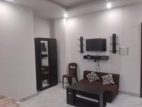 ein Wohnzimmer mit einem Sofa und einem TV an der Wand in der Unterkunft Hotel Alakhraj Palace in Hazārībāg