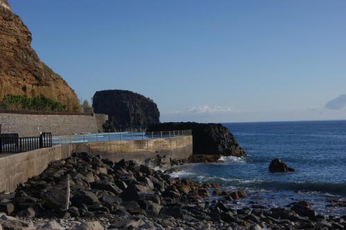 a retaining wall next to the ocean with rocks at Hotel Costa Linda in Porto da Cruz