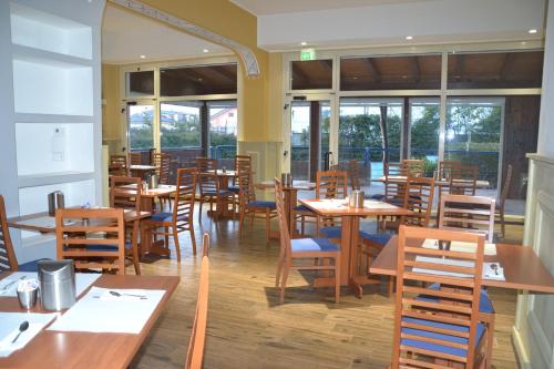 um restaurante com mesas e cadeiras de madeira e janelas em Hotel Azzurro em LʼAquila