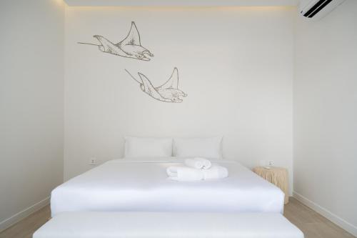 a white bedroom with a bed with two birds on the wall at The Season Resort in Ban Chamrung