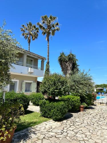 a house with palm trees and bushes in front of it at Alexandros Studios Apartments in Roda