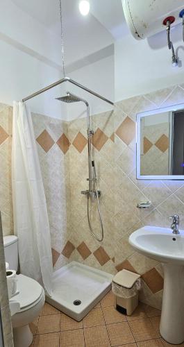 a bathroom with a shower and a toilet and a sink at Joen Apartments in Sarandë