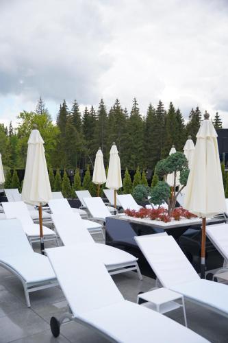 a row of white lounge chairs and tables with umbrellas at Mountain Residence Apartments & Chalet in Bukovel