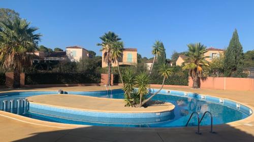 una gran piscina con palmeras. en Terrasse du golf, en Béziers