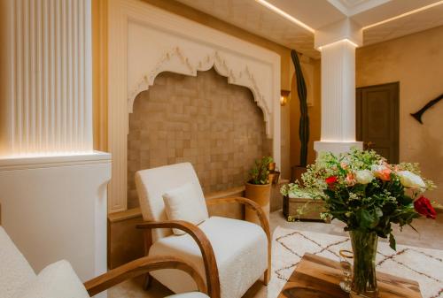 a living room with a chair and a vase of flowers at Riad Luxe Nomade Marrakech & Spa in Marrakech