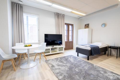 a white room with a bed and a table and a tv at Vanha Postitalo in Varkaus