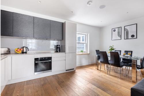 a kitchen with white cabinets and a table with chairs at 2BR in Soho - Charlotte Street - CityApartmentStay in London
