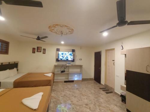 a living room with a bed and a ceiling fan at Srirathna Temple View Inn in Thanjāvūr