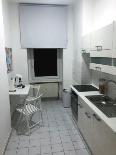 - une cuisine blanche avec un évier et une chaise dans l'établissement 750 SFT Lovely Apartment in Central Berlin Mitte, à Berlin