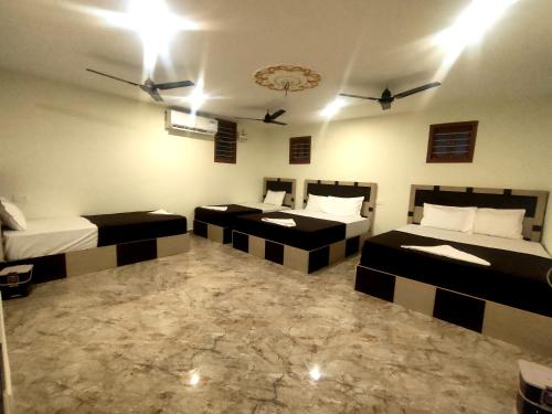 a room with three beds in a room at Srirathna Temple View Inn in Thanjāvūr