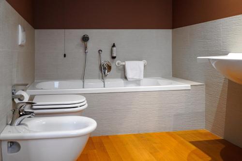a bathroom with a tub and a toilet and a sink at Hotel Arya by Mauro in Sirmione