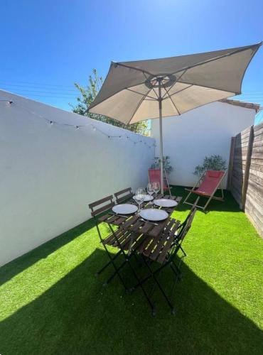 une table et des chaises avec un parasol sur une pelouse dans l'établissement Little Casa Royan, à Royan