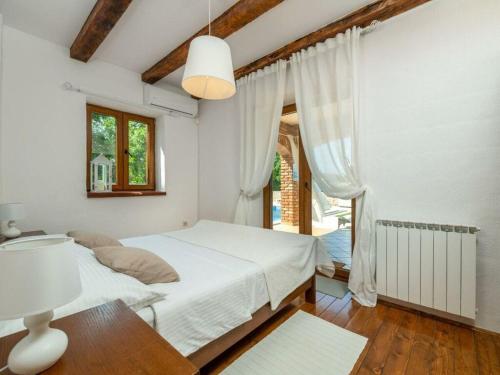 a white bedroom with a bed and a window at Villa Wish Comfortable holiday residence in Čabrunići
