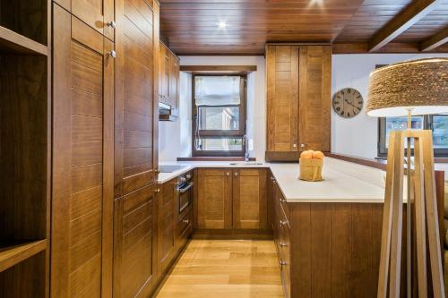 a kitchen with wooden cabinets and a clock on the wall at Luderna - Apartamento Val de Ruda A14 Montoliu in Baqueira-Beret