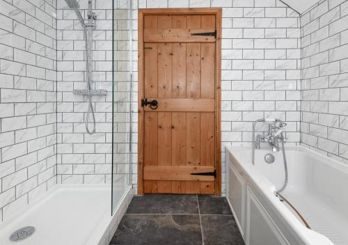 a bathroom with a bath tub and a wooden door at Glan Merion in Llanbedrog